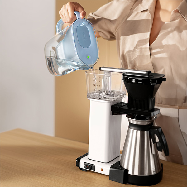Vattenfilterkanna häller filtrerat vatten i en kaffemaskin